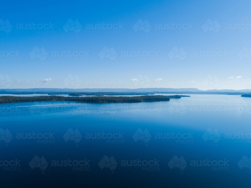 Landscape of Point Wolstoncroft in blue waters of Lake Macquarie seen from aerial view - Australian Stock Image