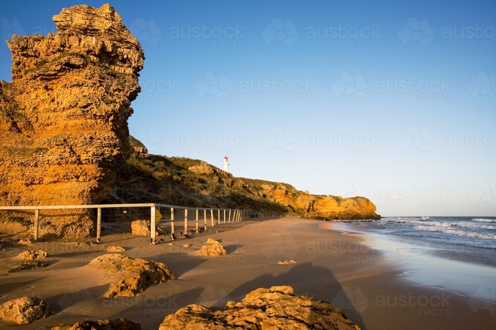 Landscape of rock face with lighthouse in background - Australian Stock Image