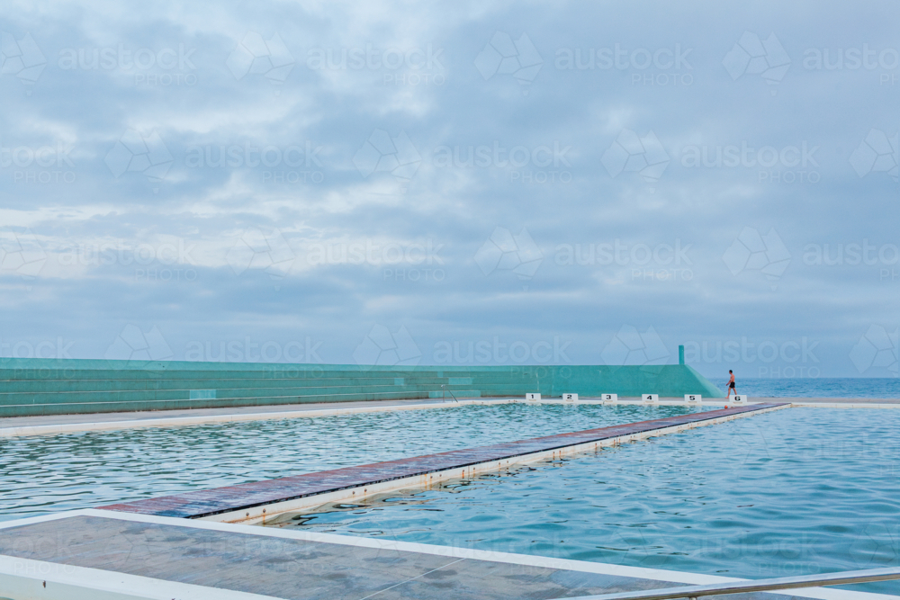 Landscape of the Newcastle Ocean Baths at dusk with blue overcast sky - Australian Stock Image