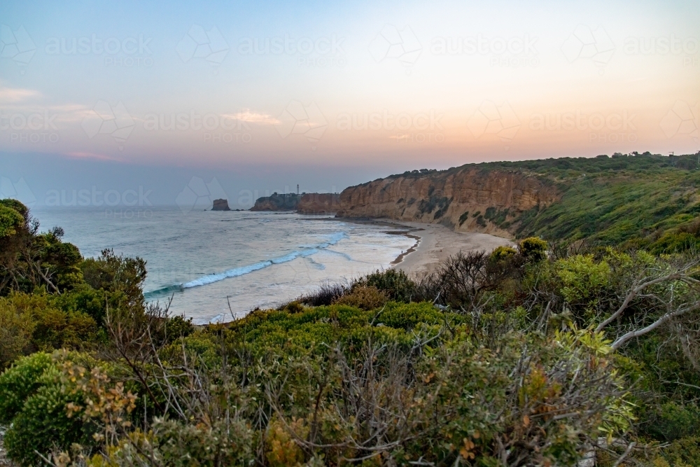 landscape view along coastline with lighthouse in the distance - Australian Stock Image