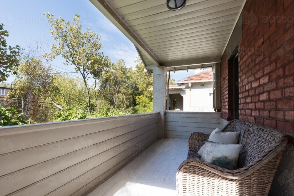 Large apartment balcony with cane outdoor seating and wood panelling - Australian Stock Image