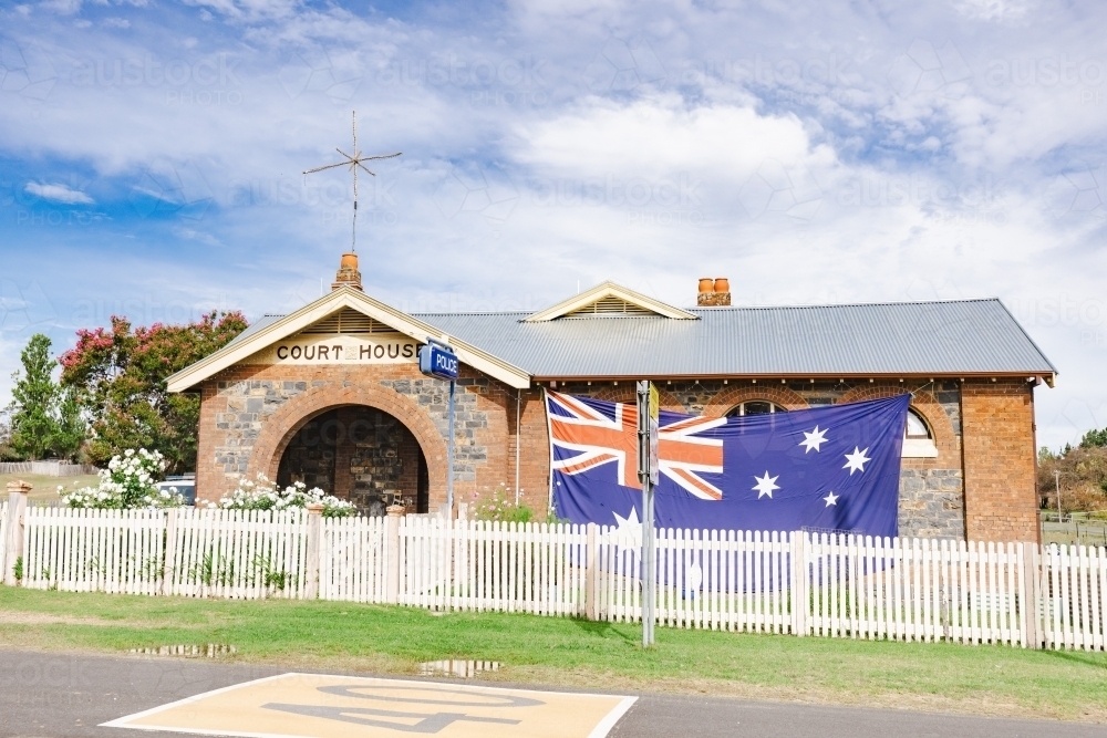 Large Australian flag flying on historic courthouse which is now a Police Station - Australian Stock Image