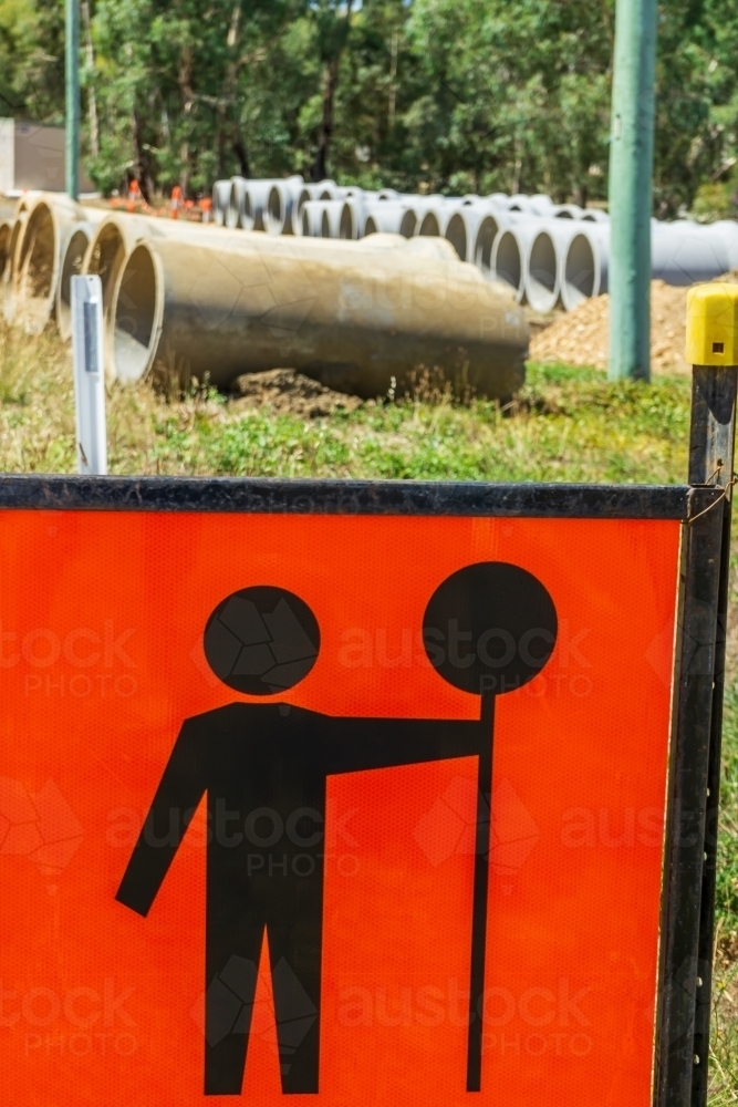 Large cement pipes laid out in rows behind a traffic sign - Australian Stock Image