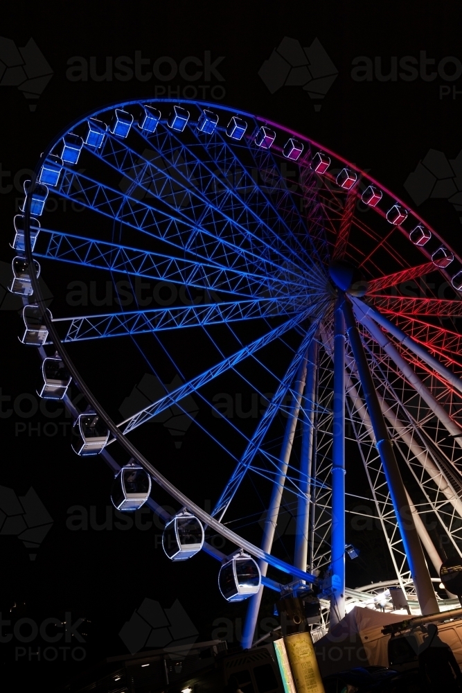 Large ferris wheel lit up at night in tricolore for Bastille Day - Australian Stock Image