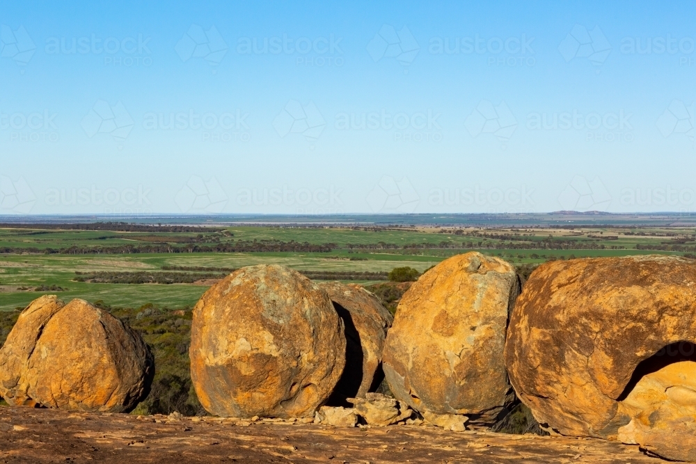 large granite boulders looking out over flat farming land - Australian Stock Image