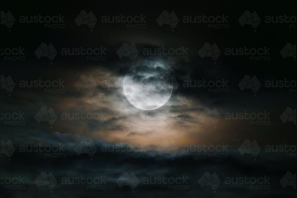 Large moon obscured in cloudy sky - Australian Stock Image