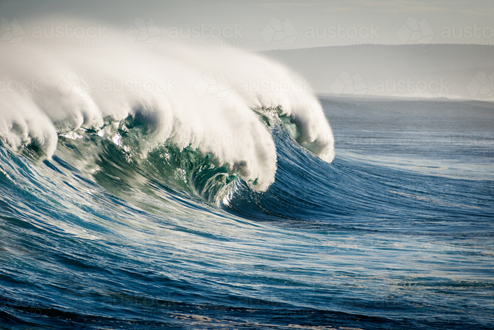 Large ocean wave curling with mist blowing off the crest - Australian Stock Image