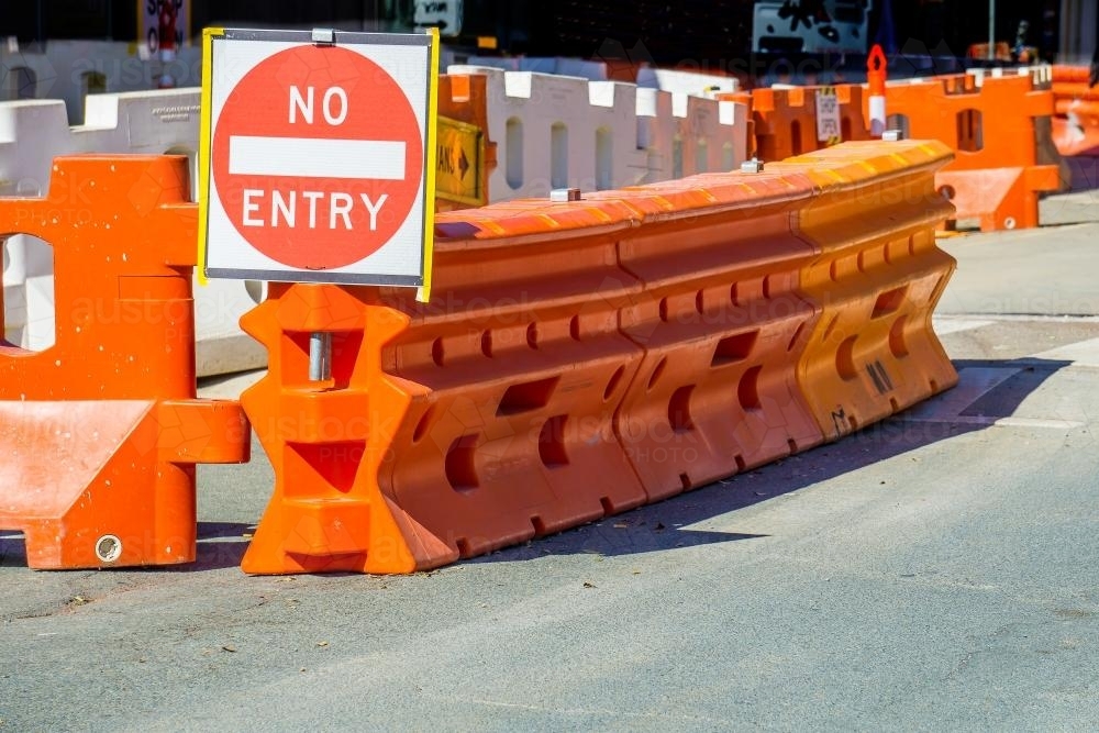 Large orange barriers and a "no entry" sign on a road - Australian Stock Image