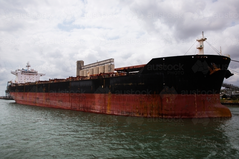 large red and black ship docked in Gladstone Harbour - Australian Stock Image