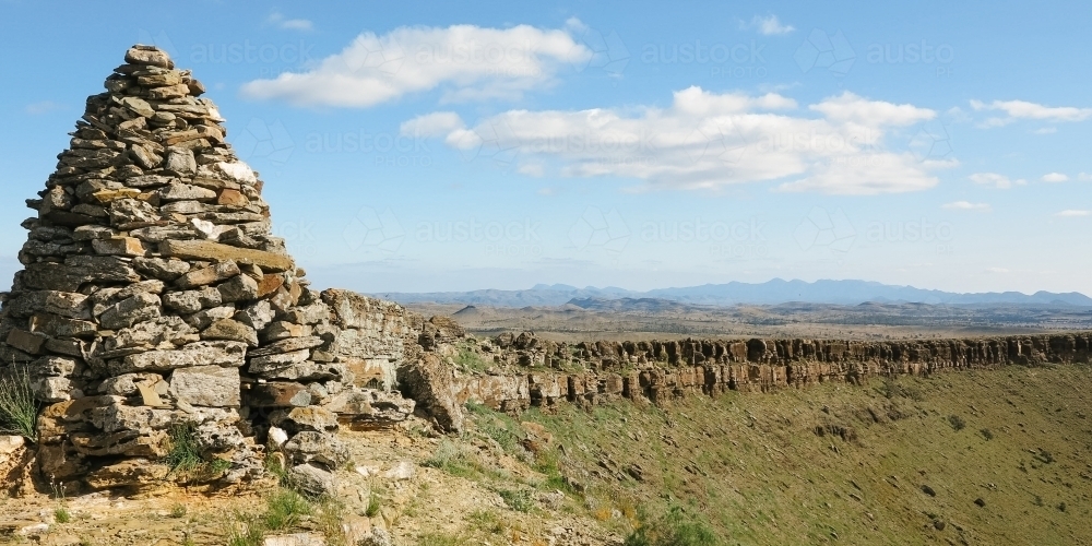 Large rock cairn with stunning rocky landscape in background - Australian Stock Image
