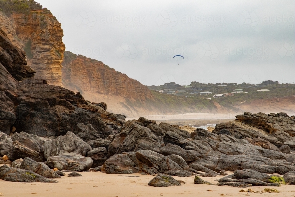 large rocks at base of cliff along beach - Australian Stock Image
