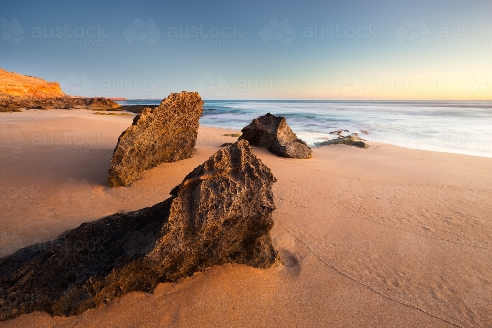 Large rocks on beach in the early morning - Australian Stock Image