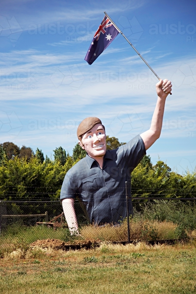 Large sculpture of man holding an Australian flag in a field - Australian Stock Image