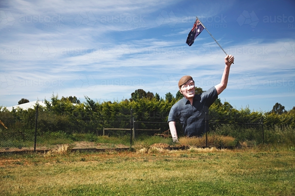 Large sculpture of man holding an Australian flag in a field - Australian Stock Image
