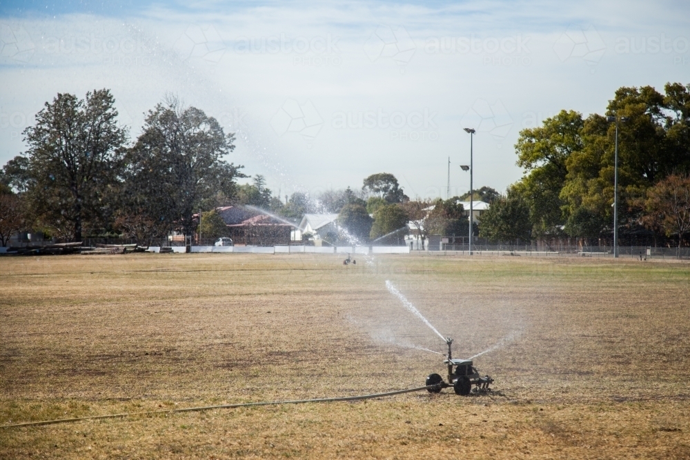 Large sprinkler watering the dry grass on the show ground - Australian Stock Image