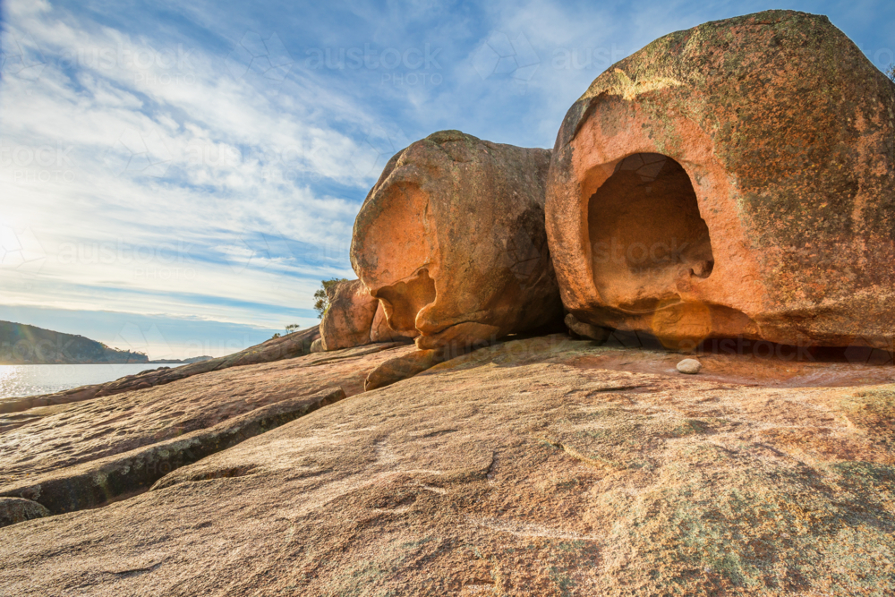 Large weathered rock formations covered in lichen, perched on a granite ledge - Australian Stock Image