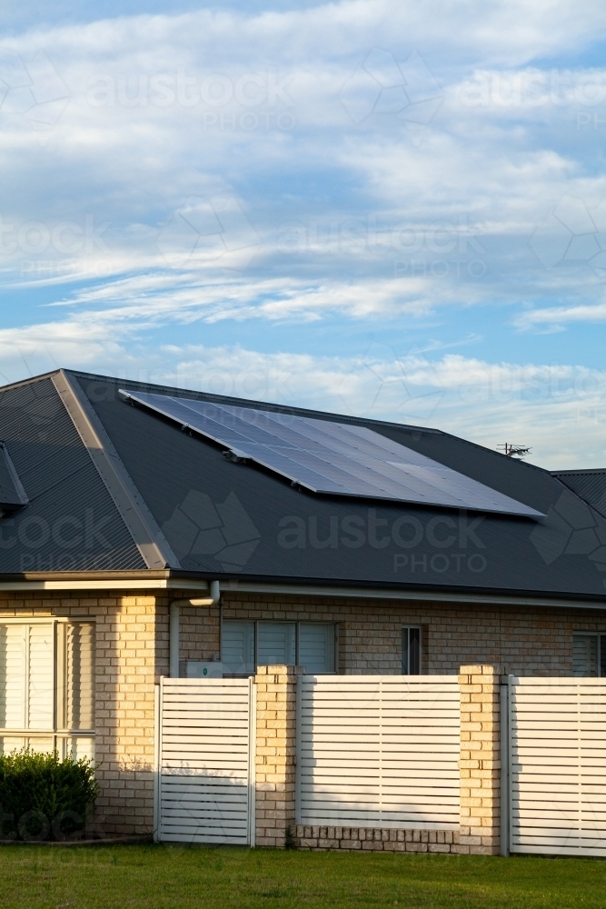 last daylight on front of house with solar panels installed on roof of home - Australian Stock Image