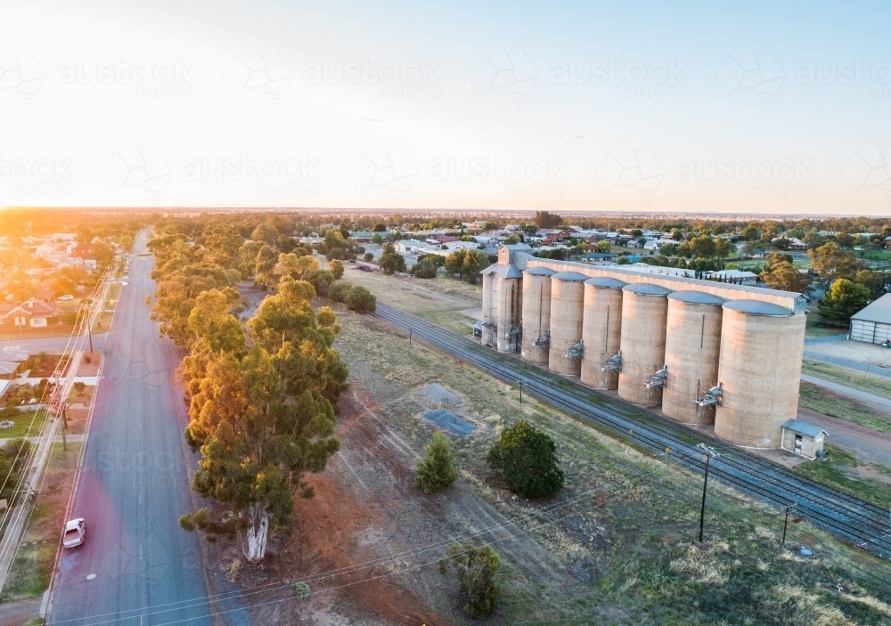 Last light of the day over train tracks and grain silos in rural country town - Australian Stock Image