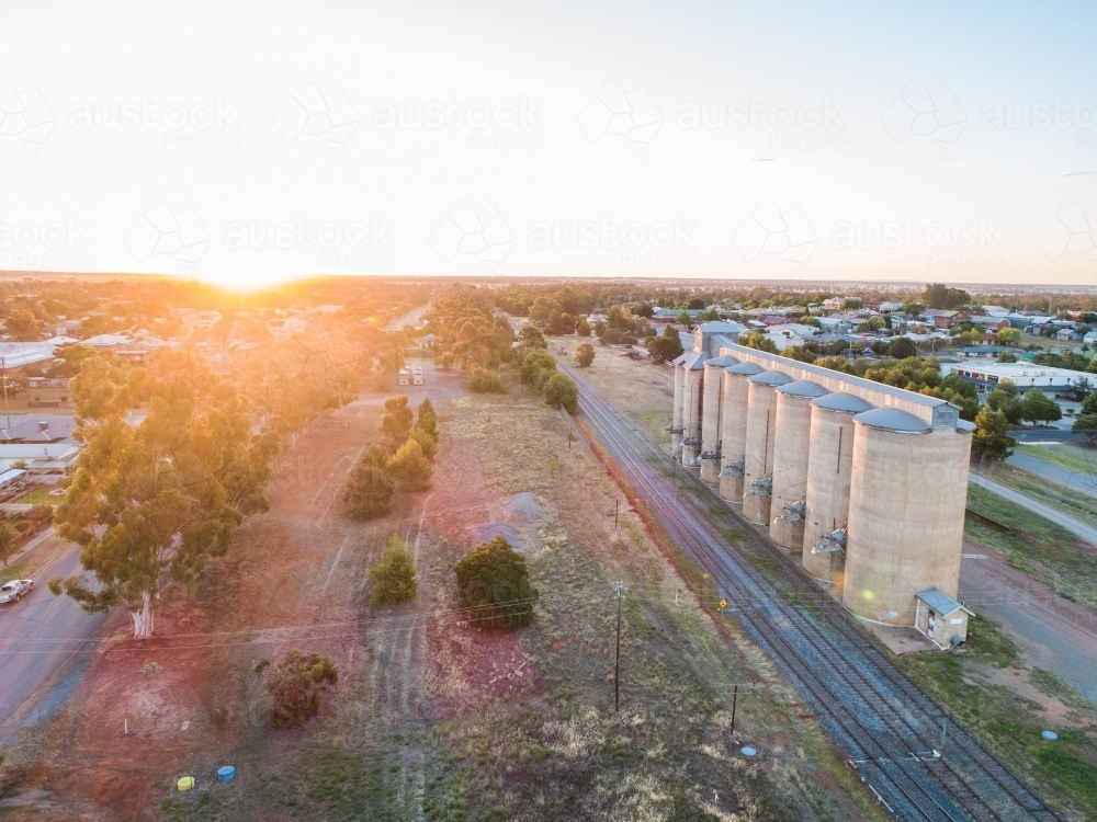 Last light of the day over train tracks and grain silos in rural country town - Australian Stock Image