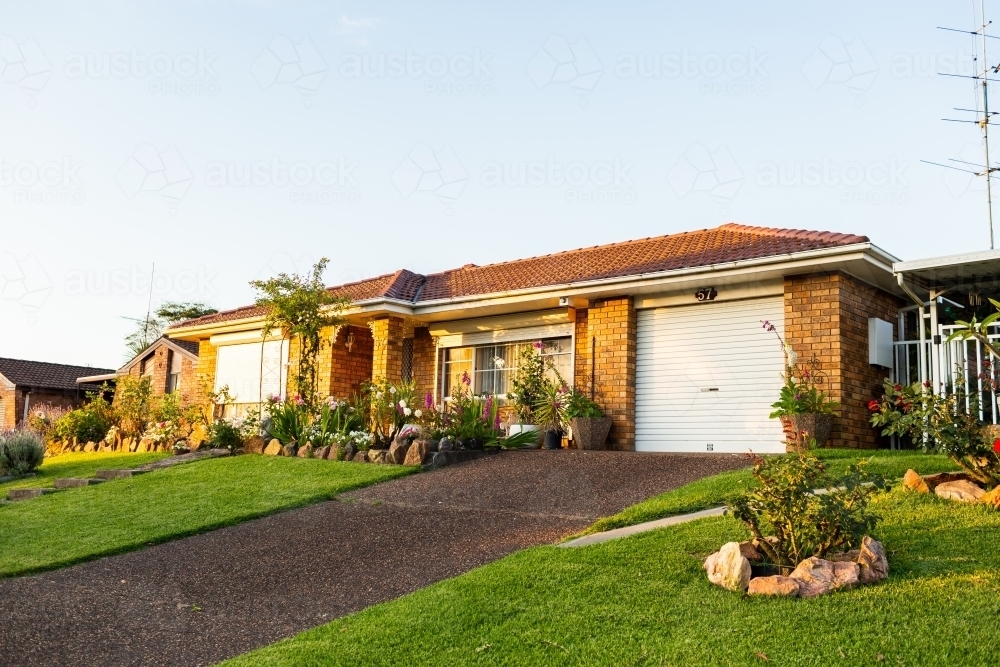 Last light of the day shining on neat front garden and porch of house - Australian Stock Image
