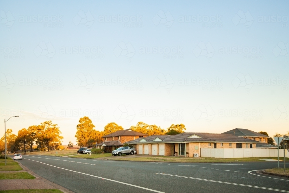 Last light on trees at intersection of quiet town street - Australian Stock Image