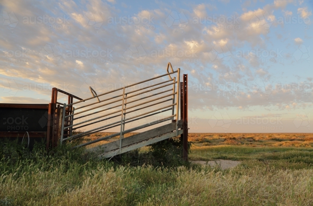 Late afternoon light across the plains with loading chute and cattle ramp - Australian Stock Image