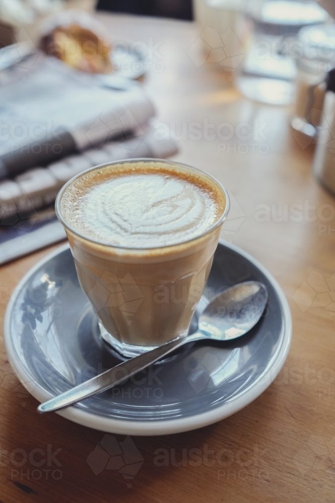 Latte coffee with newspaper on wooden table - Australian Stock Image