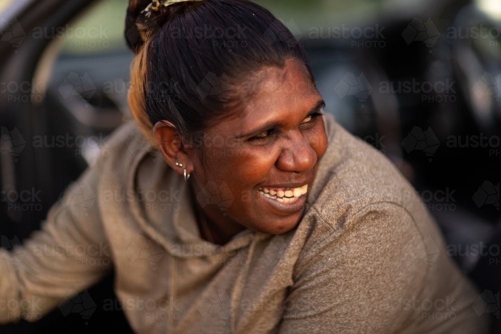 laughing smiling lady looking over her shoulder as she sits in car - Australian Stock Image