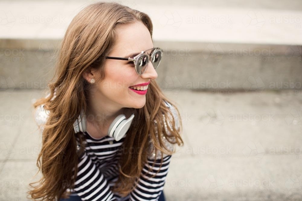 Laughing young woman looking over shoulder with headphones - Australian Stock Image