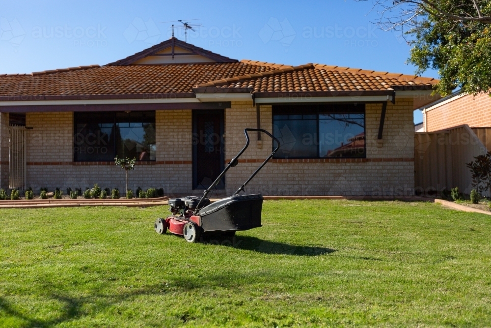 Lawnmower on land outside suburban home - Australian Stock Image
