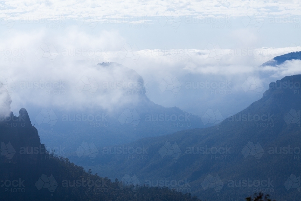 Layered mountains and valleys shrouded in cloud and mist - Australian Stock Image