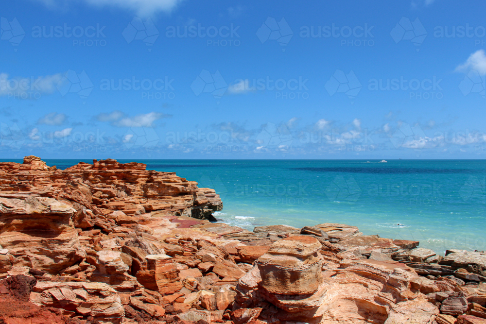 Layered red rocks along the waters edge - Australian Stock Image