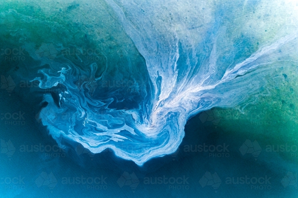 Leachate flowing off tidal mud flats near an anchored yacht. - Australian Stock Image