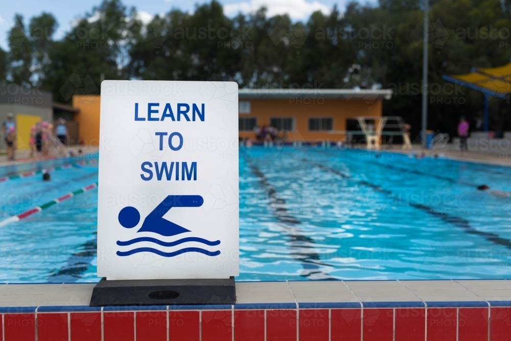 Image of Learn to swim sign at a swimming pool - Austockphoto