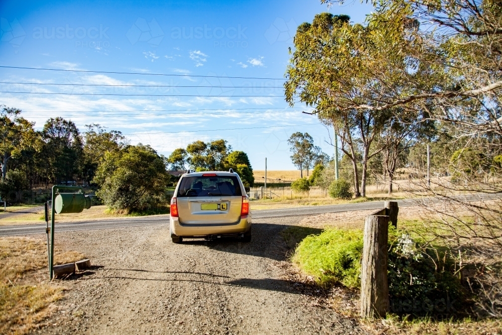 Learner driver in car turning out of the driveway onto the road - Australian Stock Image