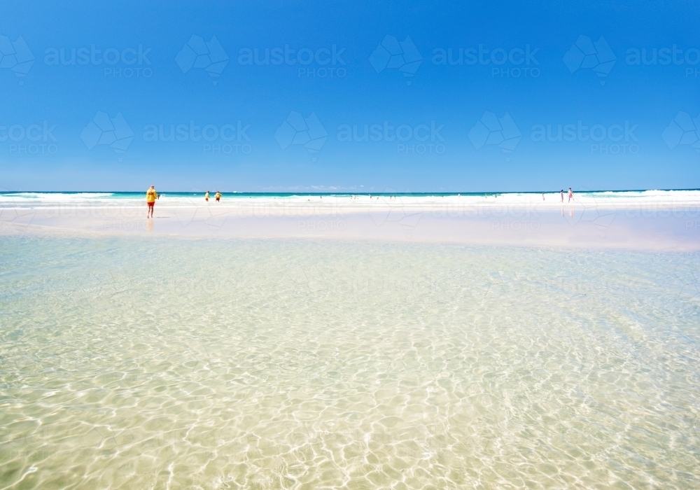 Leaving the beach into the clear ocean waters with the lifesaver in the distance - Australian Stock Image