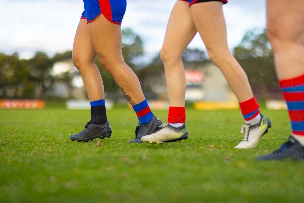 legs feet and boots of football players running on green grass - Australian Stock Image