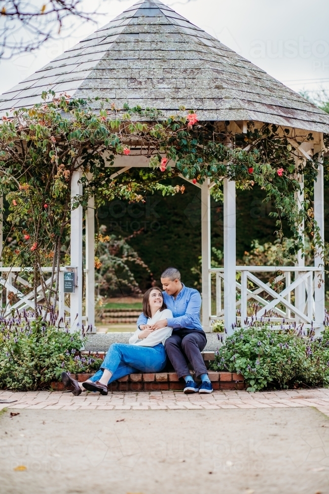 lgbtqi couple being cozy in a gazebo with flowers and vines - Australian Stock Image
