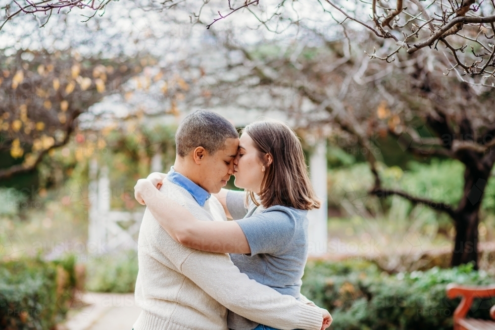 Lgbtqi couple being intimate and hugging each other with trees in the background - Australian Stock Image