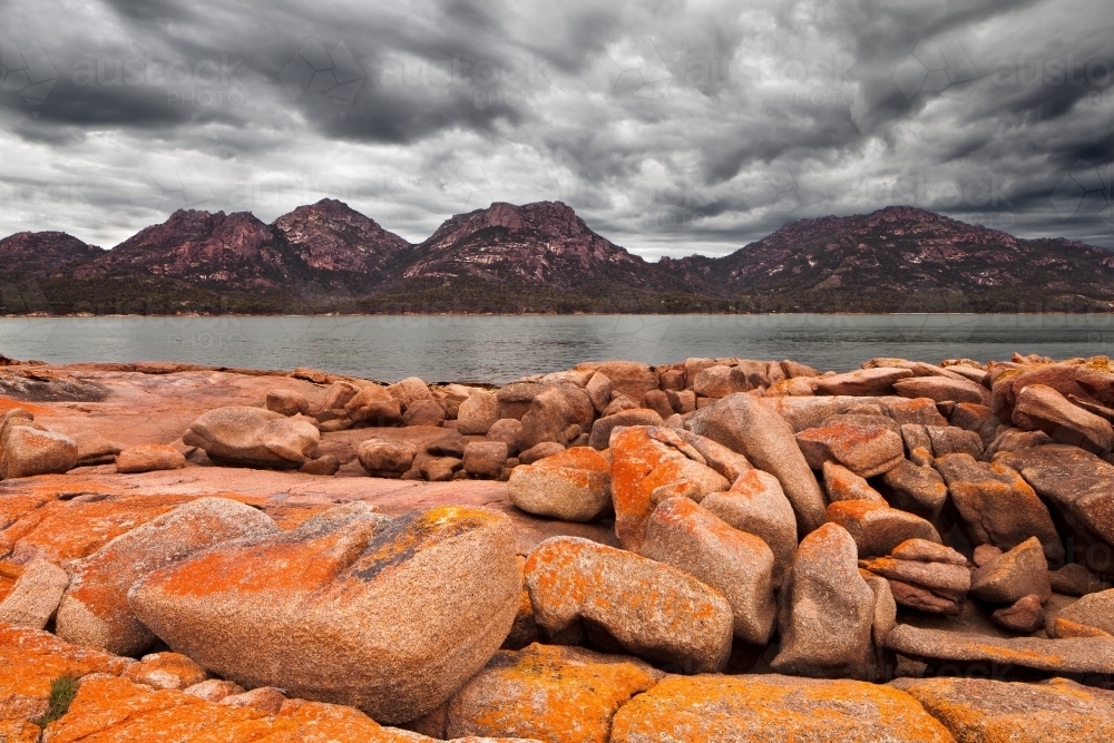 Lichen covered rocks and stormy sky at Coles Bay - Australian Stock Image