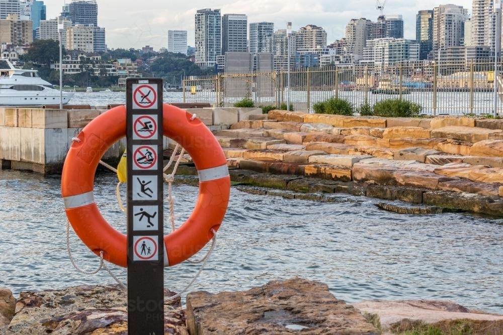 Lifebuoy at city harbour with buildings in distance - Australian Stock Image