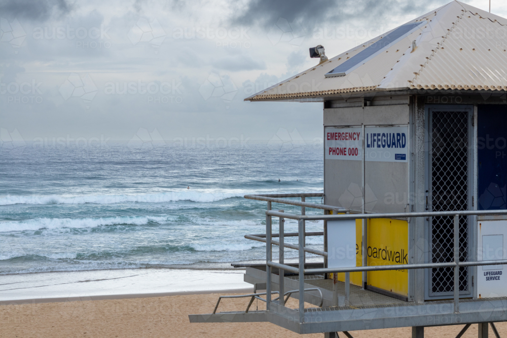 Lifeguard tower on the sand in front of the ocean with an overcast sky - Australian Stock Image