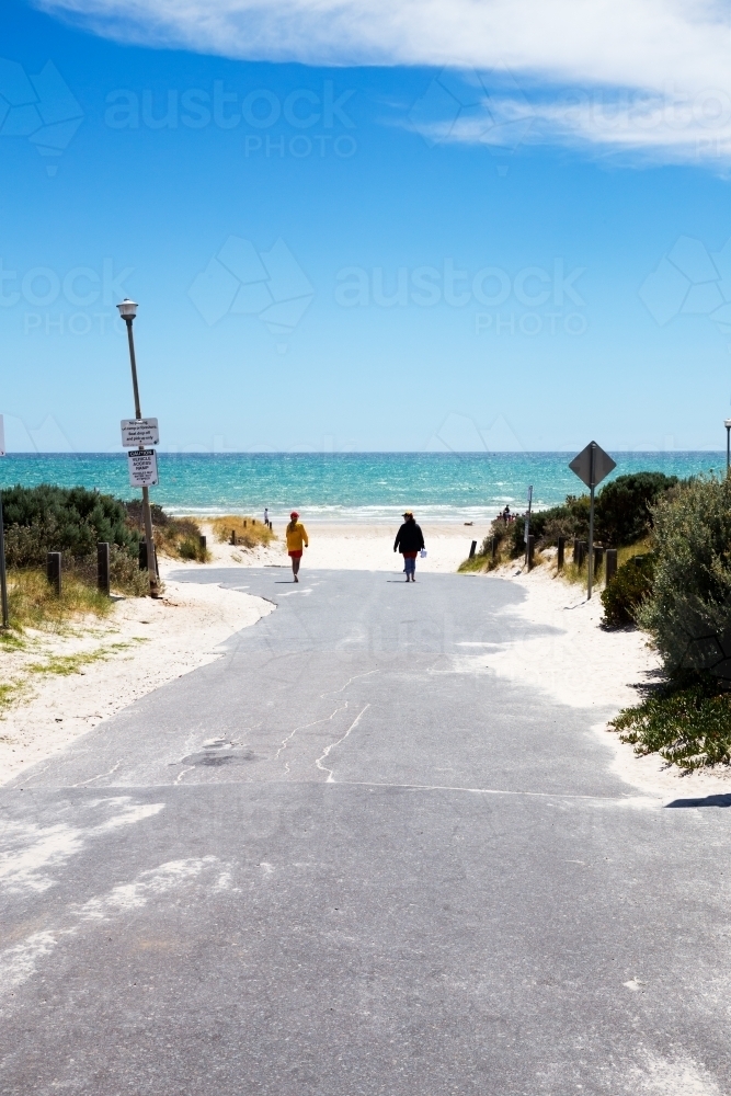 Lifesaver walking down to beach along access road vertical - Australian Stock Image