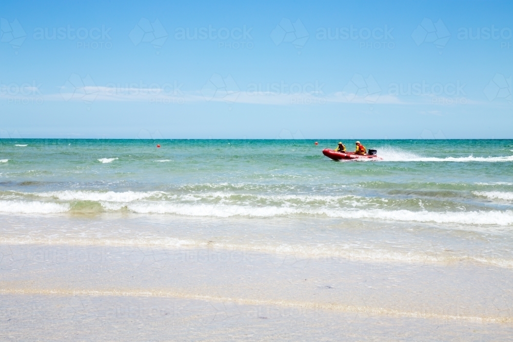 Lifesavers patrolling beach in rubber dinghy - Australian Stock Image