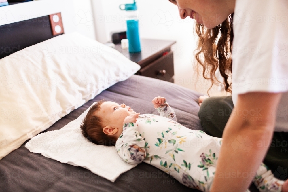 Lifestyle shot of happy mother and baby interacting together in bedroom - Australian Stock Image