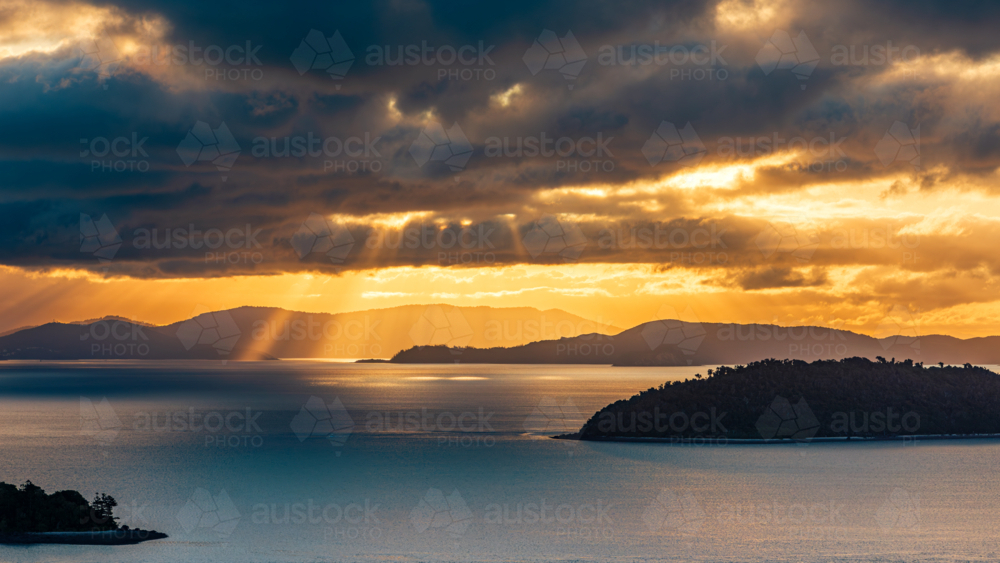 Light Breaking Through Clouds during Sunset over the Whitsundays as seen from Hamilton Island - Australian Stock Image