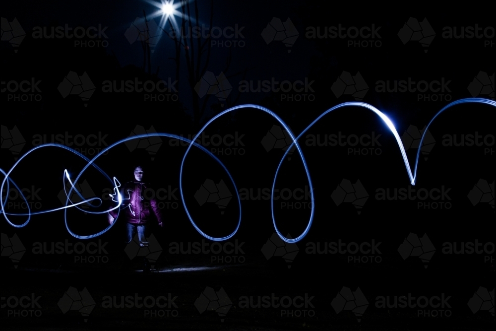 Light trails from a torch and the moon with person standing in darkness - Australian Stock Image