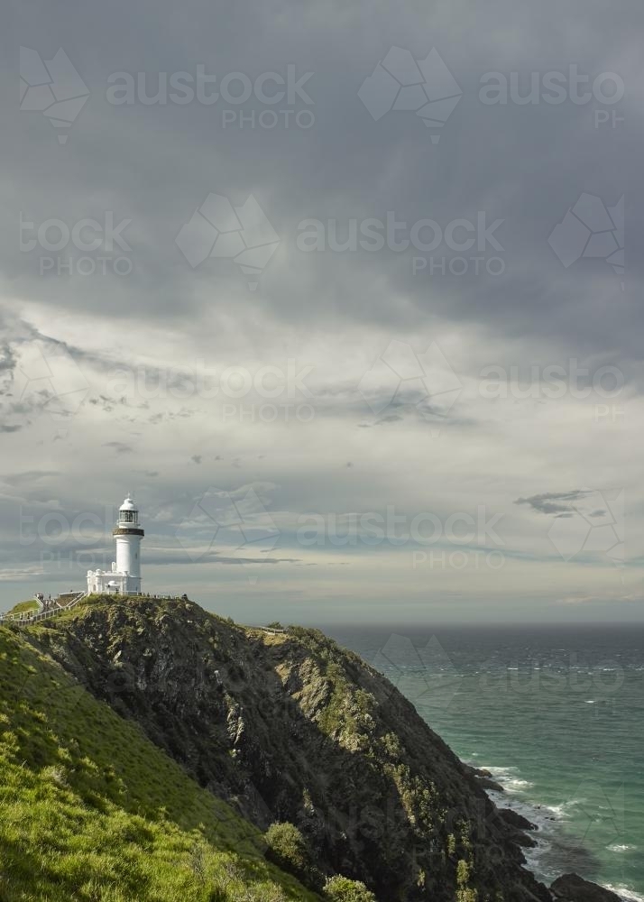 Lighthouse on headland against stormy sky - Australian Stock Image