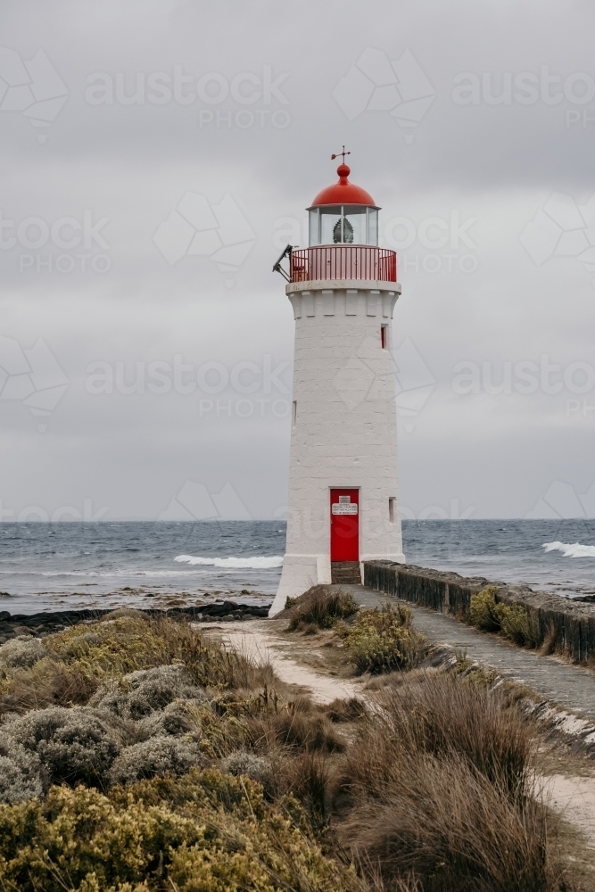 Lighthouse standing tall against the ocean. - Australian Stock Image