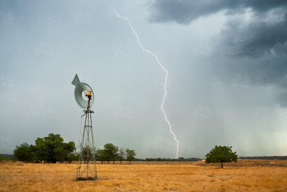 Lightning strikes ahead of a thunderstorm on farmland - Australian Stock Image